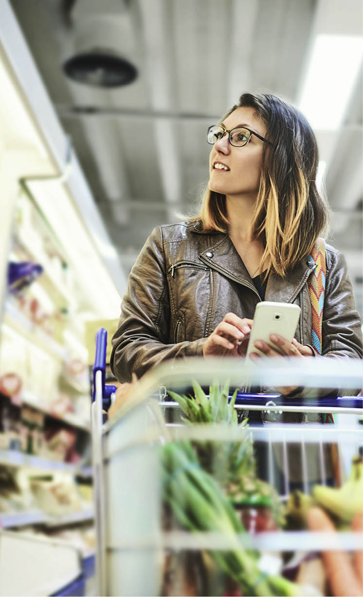 Shot of a young woman using a mobile phone in a grocery store